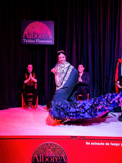 Flamenco dancer performing at La Alboreá Tablao Flamenco with musicians on stage.