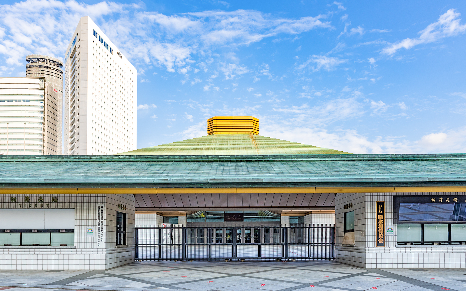 Ryogoku Kokugikan sumo arena entrance in Tokyo, Japan, with modern buildings in the background.