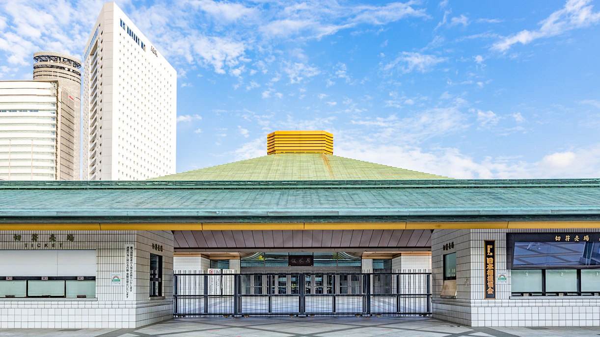 Ryogoku Kokugikan sumo arena entrance in Tokyo, Japan, with modern buildings in the background.
