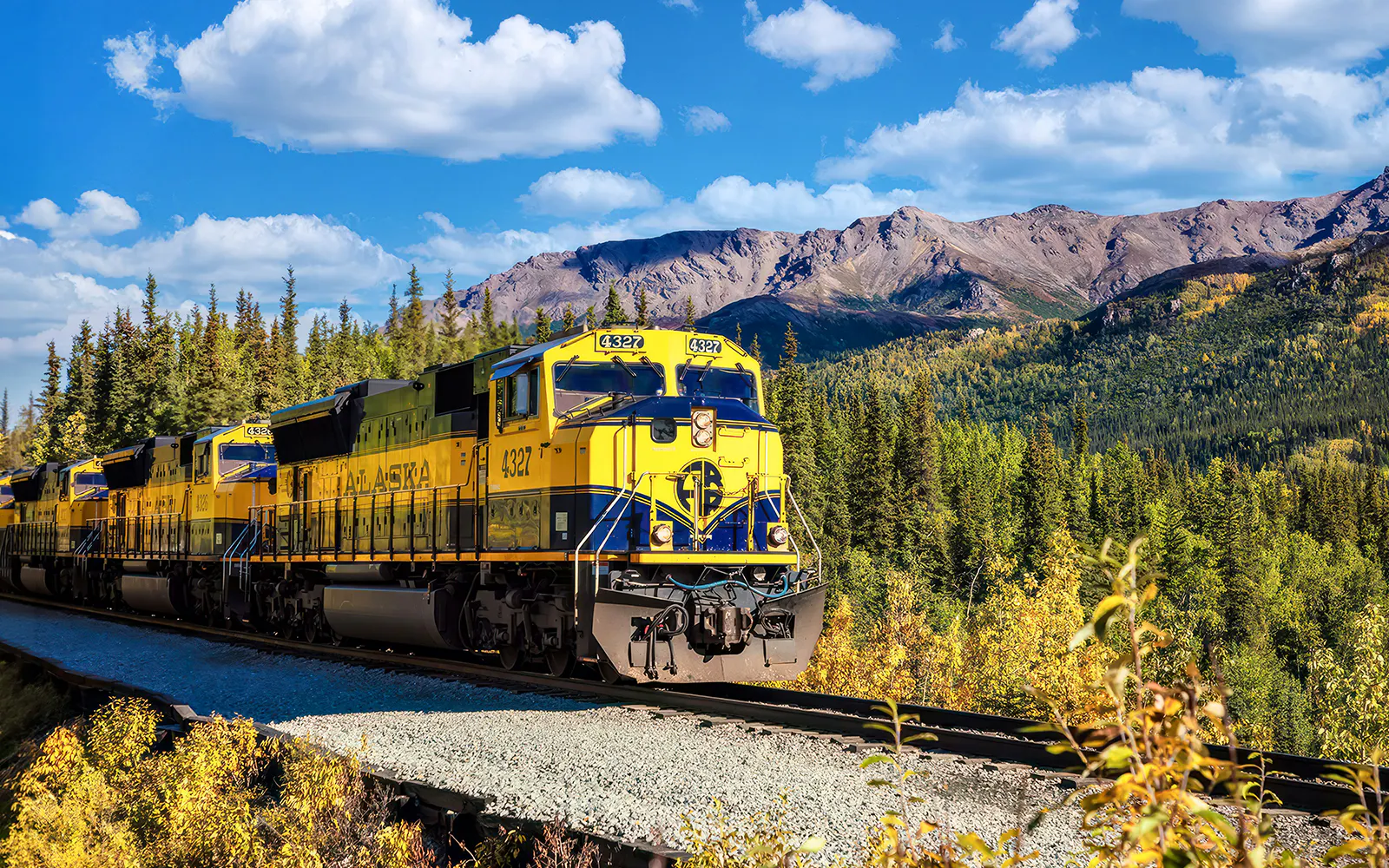 Alaska Railroad train traveling through scenic mountain landscape.