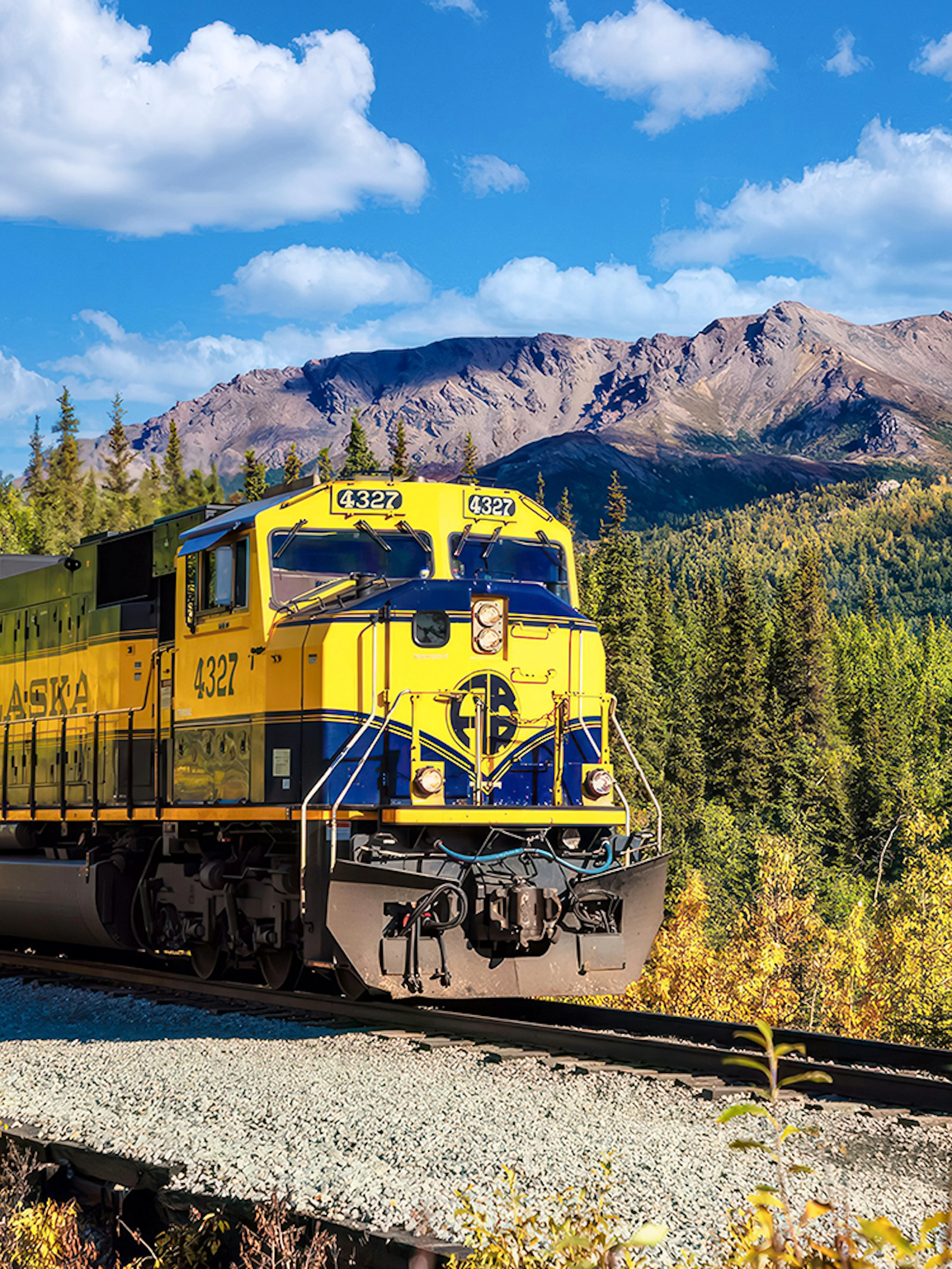 Alaska Railroad train traveling through scenic mountain landscape.