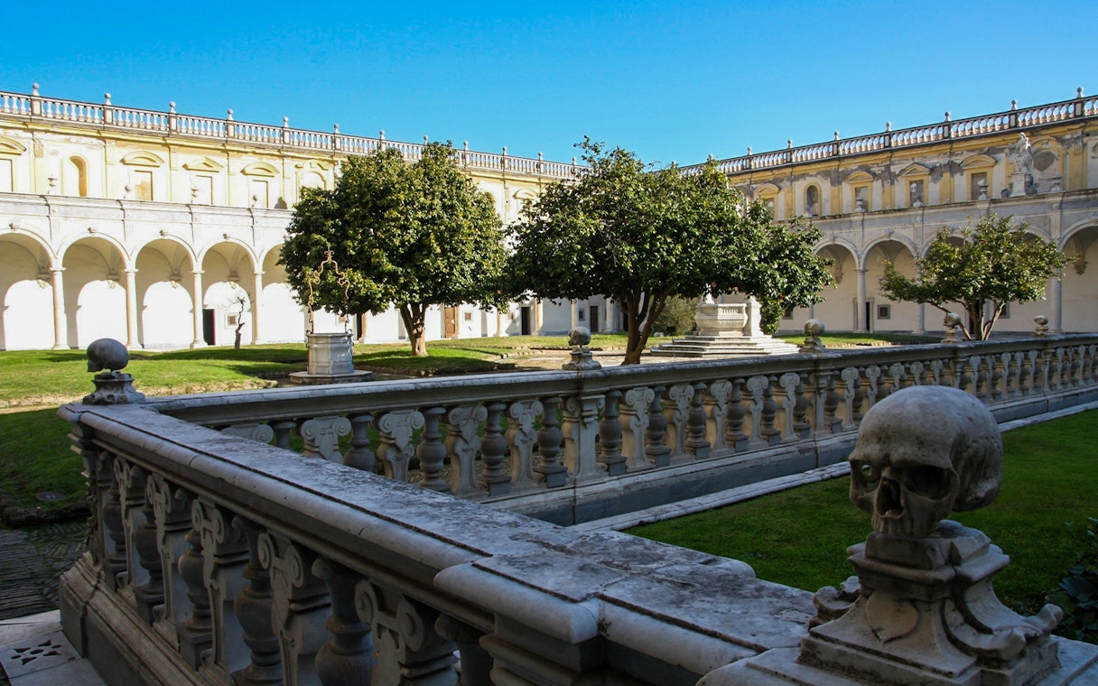Courtyard of Certosa di San Martino in Naples with stone balustrade and trees.