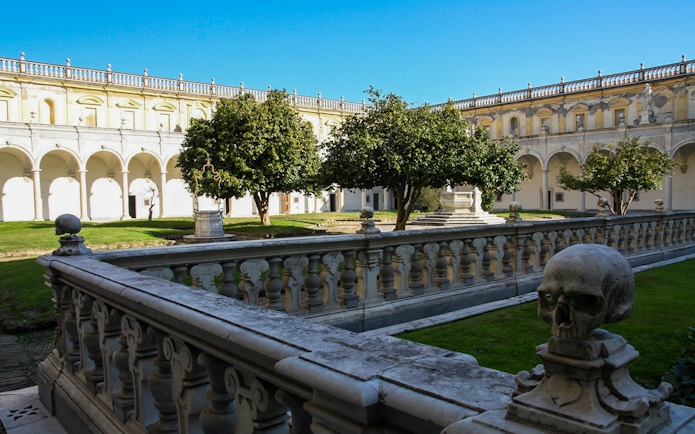 Courtyard of Certosa di San Martino in Naples with stone balustrade and trees.