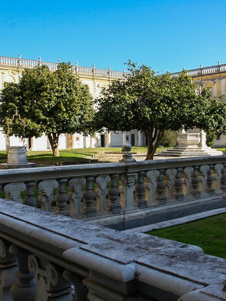 Courtyard of Certosa di San Martino in Naples with stone balustrade and trees.