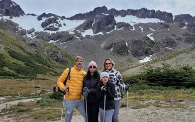 Tourists hiking on Ushuaia Martial Glacier with snowy peaks in the background.