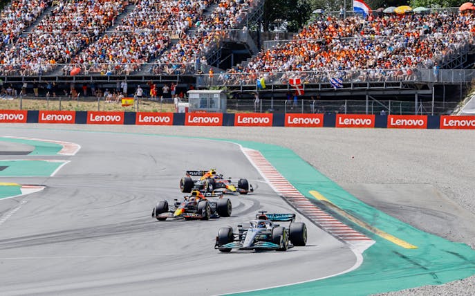 Formula 1 cars racing on Circuit de Barcelona-Catalunya with full grandstand.
