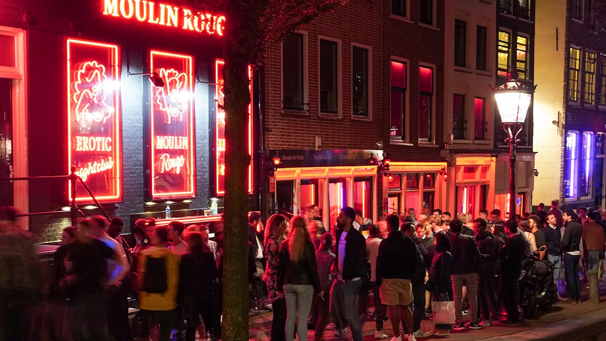 Crowd outside Moulin Rouge in Amsterdam's Red Light District at night.