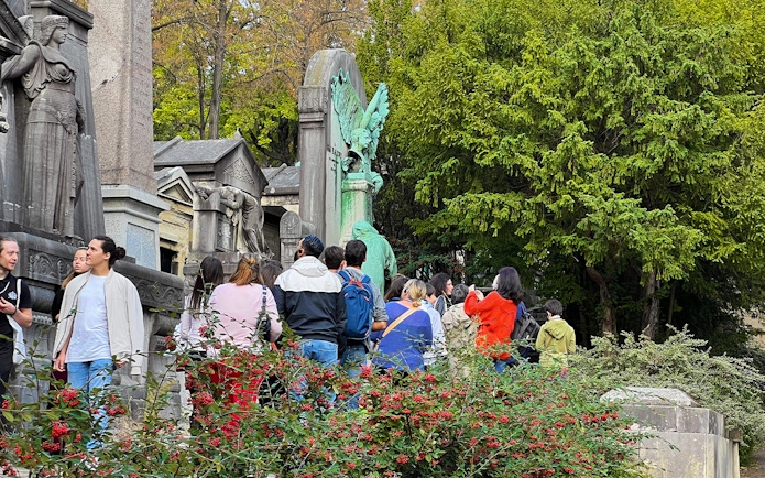 Visitors exploring statues and tombs at Père Lachaise Cemetery, Paris.