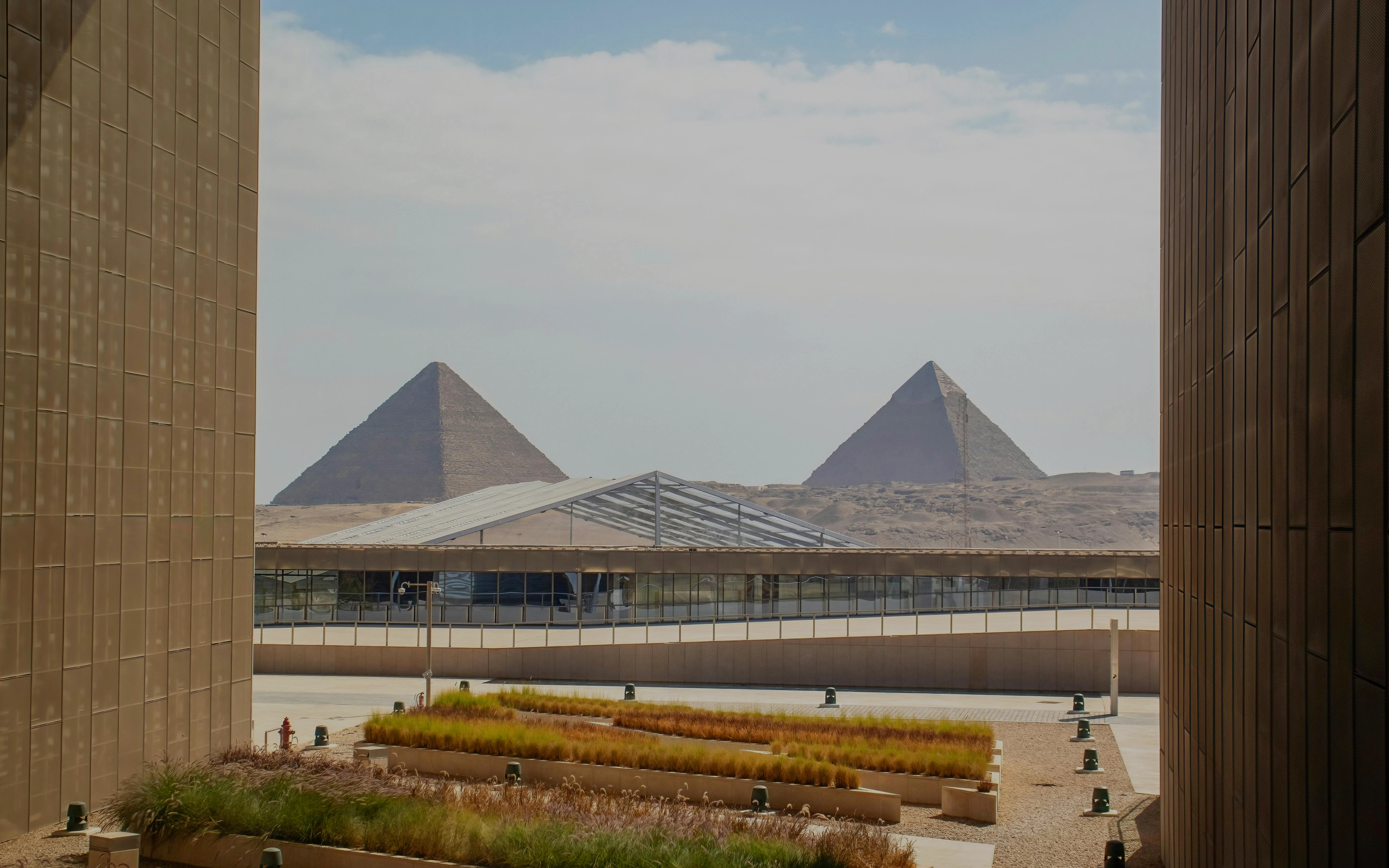 Visitors exploring the Grand Egyptian Museum interior with large statue and modern architecture.