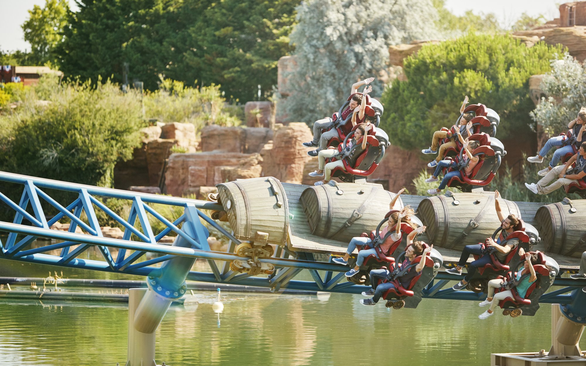 Riders on Furius Baco roller coaster at PortAventura over water.