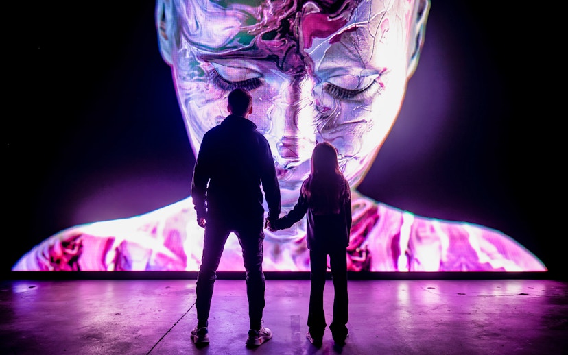 Visitors at AMAZE Amsterdam viewing a large digital face display.