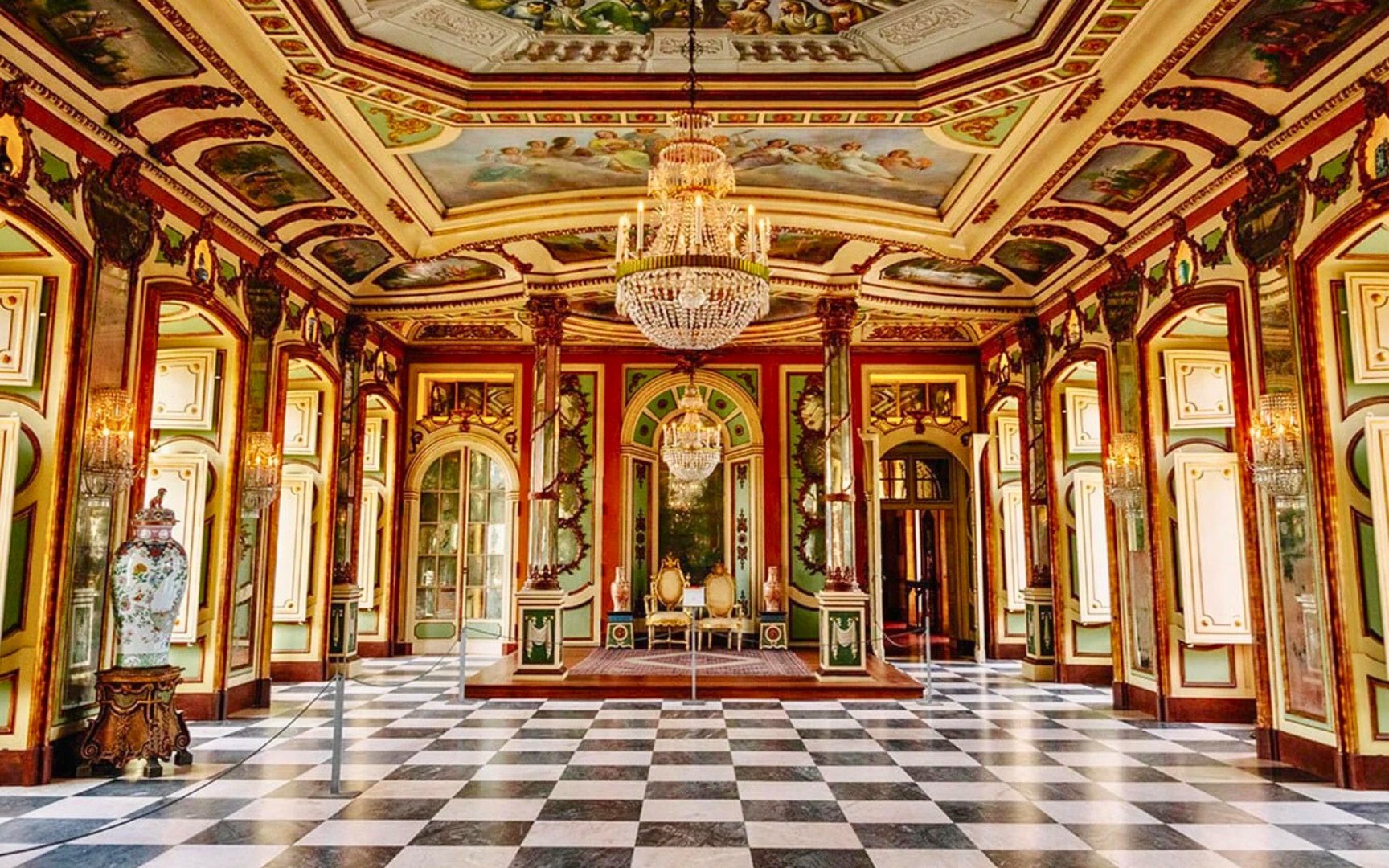 Interior of National Palace of Queluz with ornate chandeliers and decorative ceiling.