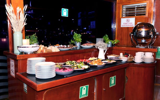 Buffet setup on Abu Dhabi Dhow Dinner Cruise with plates, salads, and bread.
