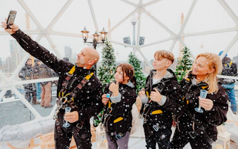 Guests enjoying the Up at the O2 Snow Globe Experience in winter gear.