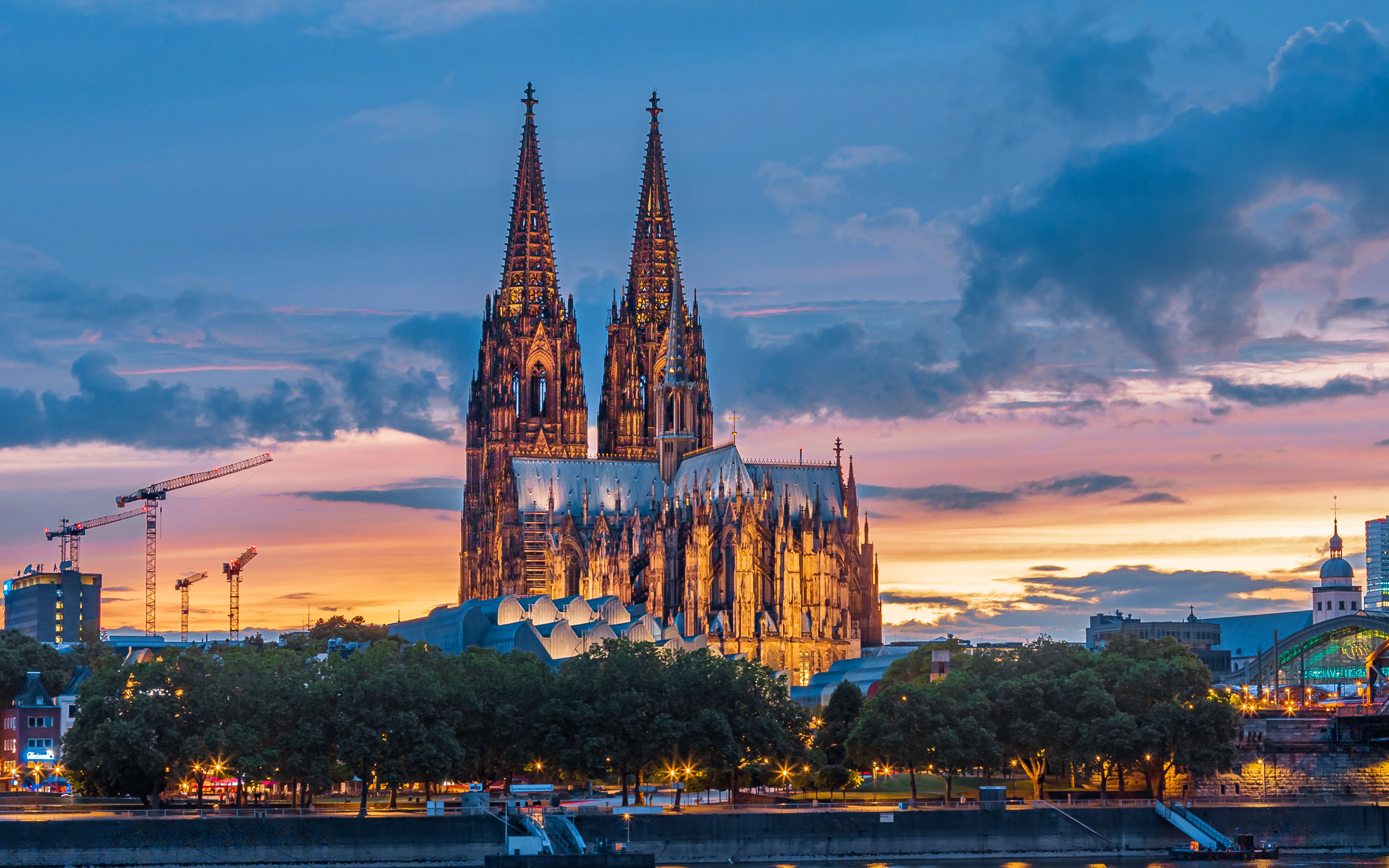 Cathedral of Cologne at sunset with illuminated spires and colorful sky.