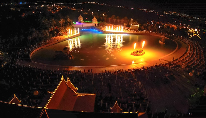 Siam Park illuminated at night with vibrant lights reflecting on the water.