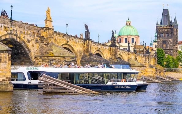 Cruise boat on Vltava River near Charles Bridge in Prague.