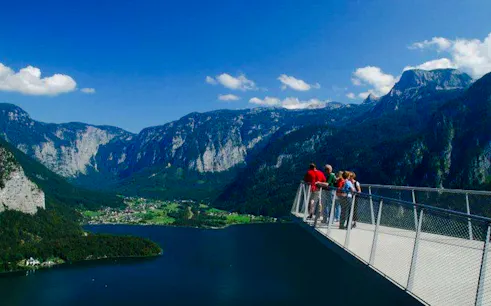 Visitors on Hallstatt Skywalk overlooking mountains and lake, part of Salzburg private tour.
