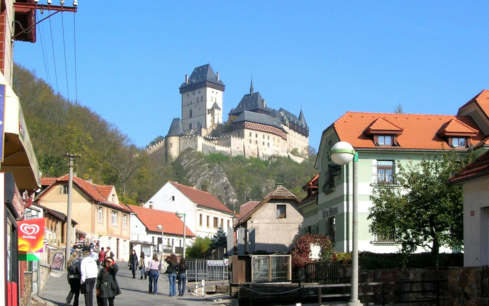 Karlstejn Castle view from village street with people walking, Czech Republic.