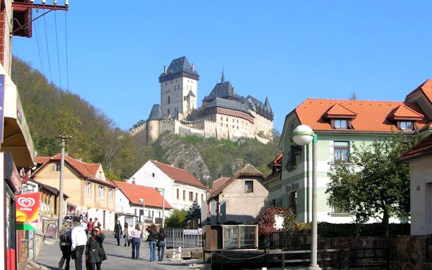 Karlstejn Castle view from village street with people walking, Czech Republic.