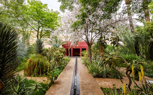 Islamic Charbagh Garden with lush greenery and a red pavilion at Jardin Secret.