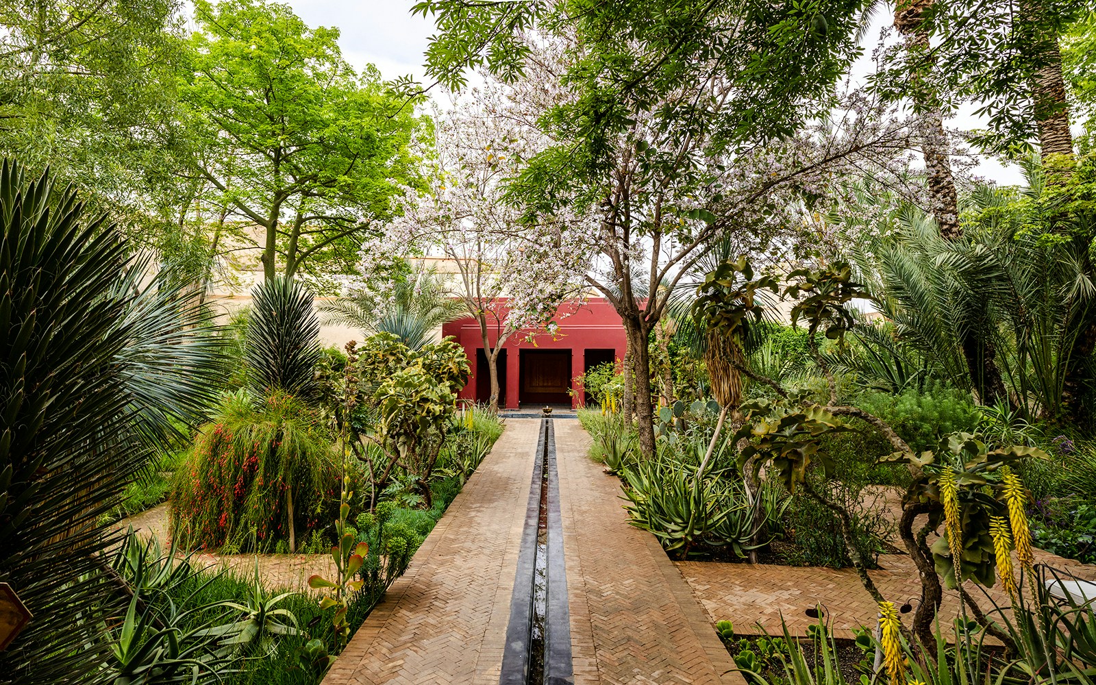 Islamic Charbagh Garden with lush greenery and a red pavilion at Jardin Secret.