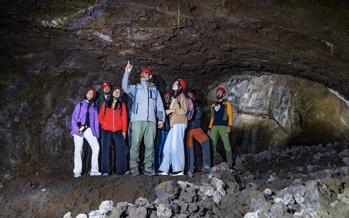 Group exploring a lava cave on Mount Etna during a morning tour in Catania.