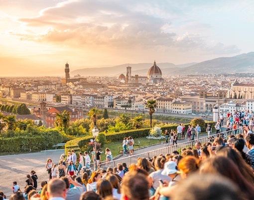 Crowd enjoying sunset view of Florence from Piazzale Michelangelo, featuring the Duomo and cityscape.