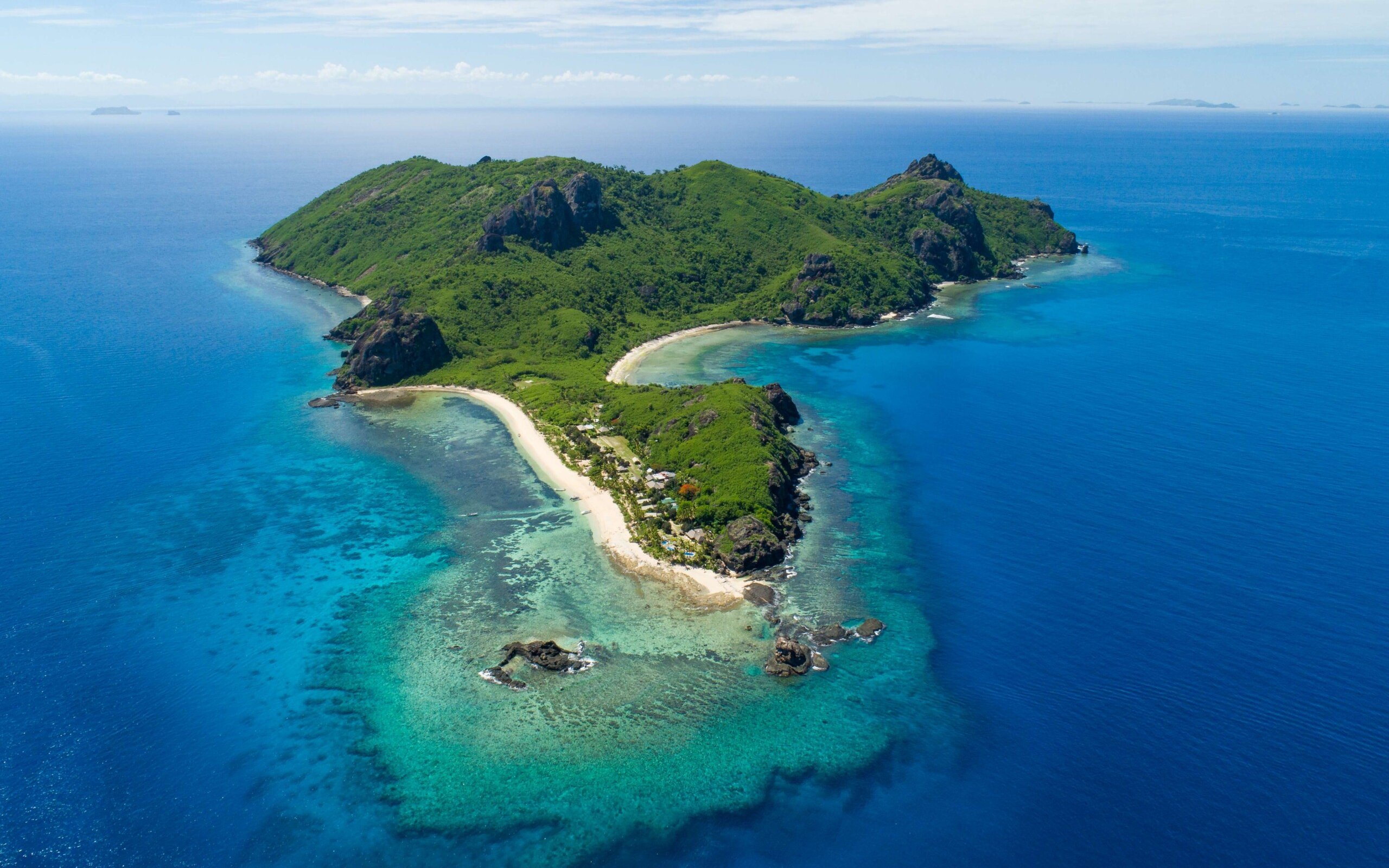 Aerial view of Kuata Island, Fiji with lush greenery and surrounding blue ocean.