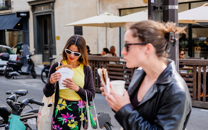 Person examining a polaroid while enjoying food on the Emily in Paris Food Tour.