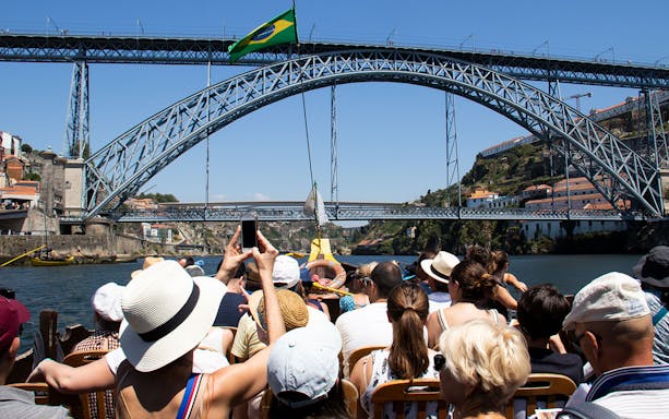 Tourists on a boat under Dom Luís I Bridge in Porto, Portugal.