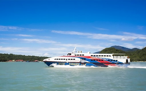 Langkawi ferry cruising on turquoise waters with lush green hills in the background.