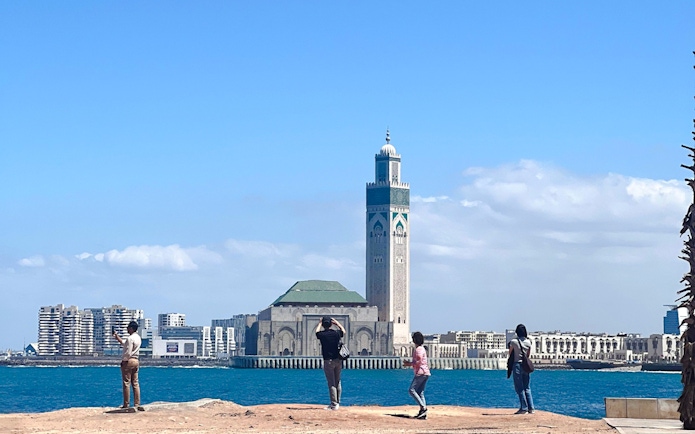 Hassan II Mosque in Casablanca with tourists by the waterfront.