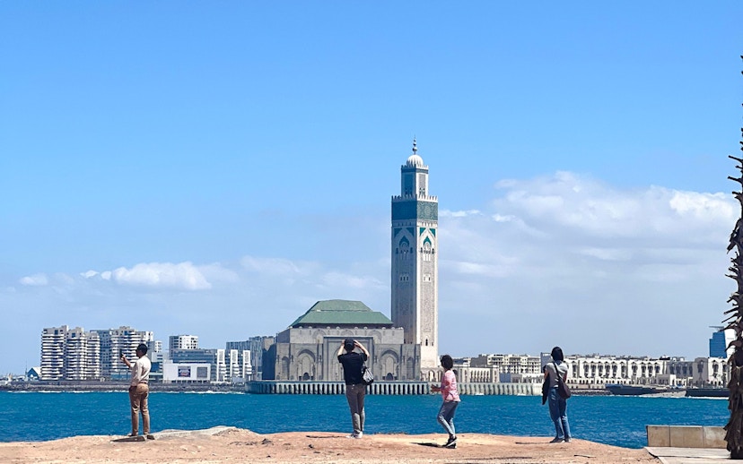 Hassan II Mosque in Casablanca with tourists by the waterfront.