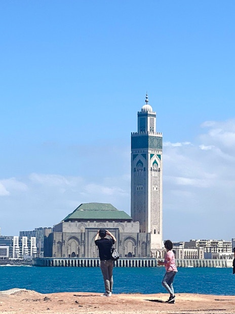 Hassan II Mosque in Casablanca with tourists by the waterfront.