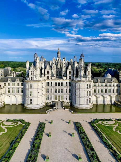 Aerial view of Chambord Castle with gardens and surrounding landscape.