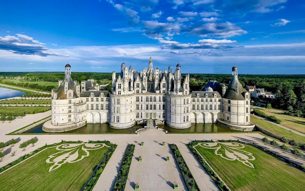 Aerial view of Chambord Castle with gardens and surrounding landscape.
