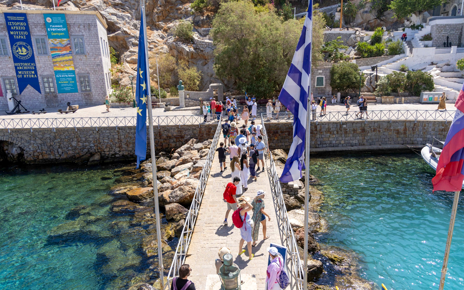 Guests walking on a pier towards the Historical Archives Museum of Hydra, Greece.