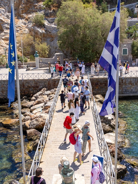 Guests walking on a pier towards the Historical Archives Museum of Hydra, Greece.
