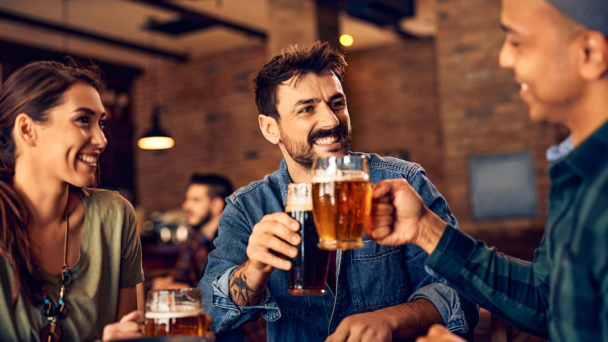 People enjoying beer together in a lively pub setting.