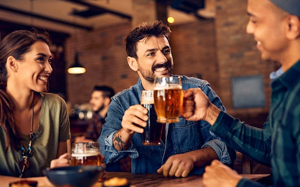 People enjoying beer together in a lively pub setting.