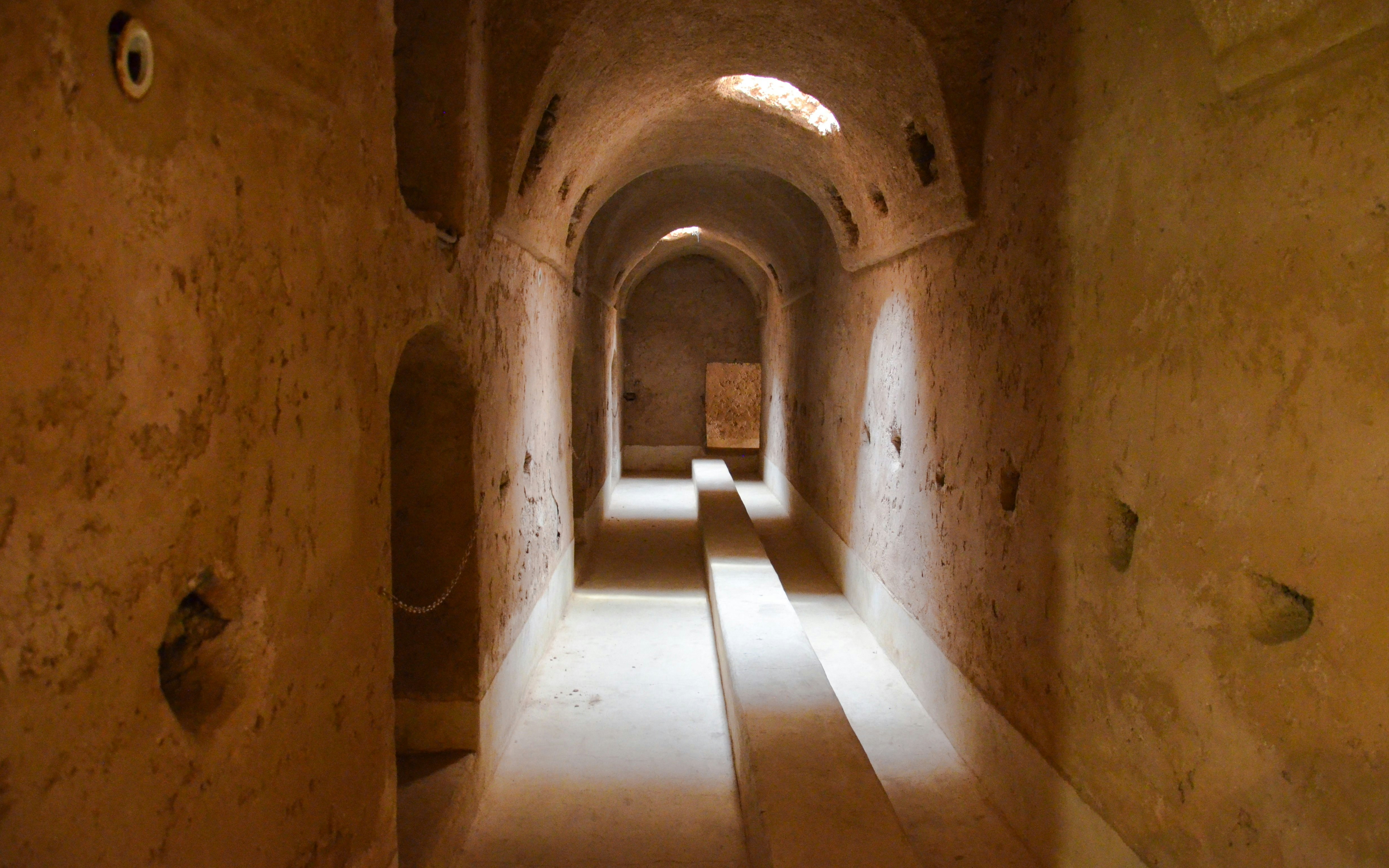 Underground corridor at El Badi Palace, Marrakech, with arched ceiling and stone walls.