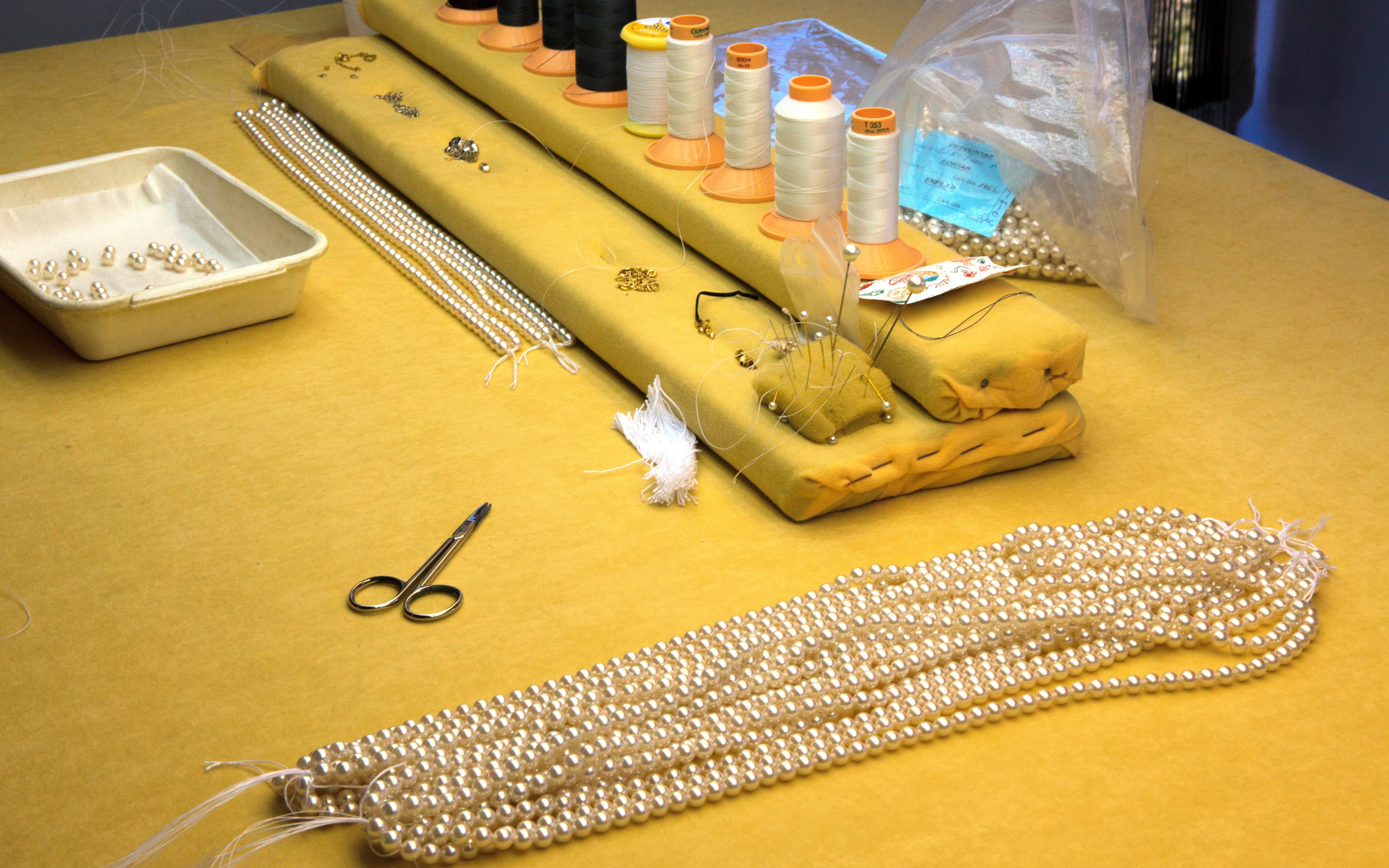 Pearl stringing station at a Mallorca factory with tools and materials.