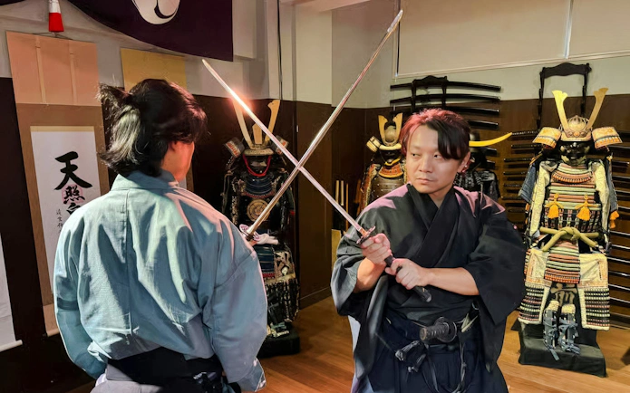 Samurai sword fight demonstration at Samurai Experience with traditional armor in background.