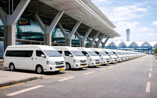 Private airport transfer vans parked outside Suvarnabhumi Airport, Bangkok.