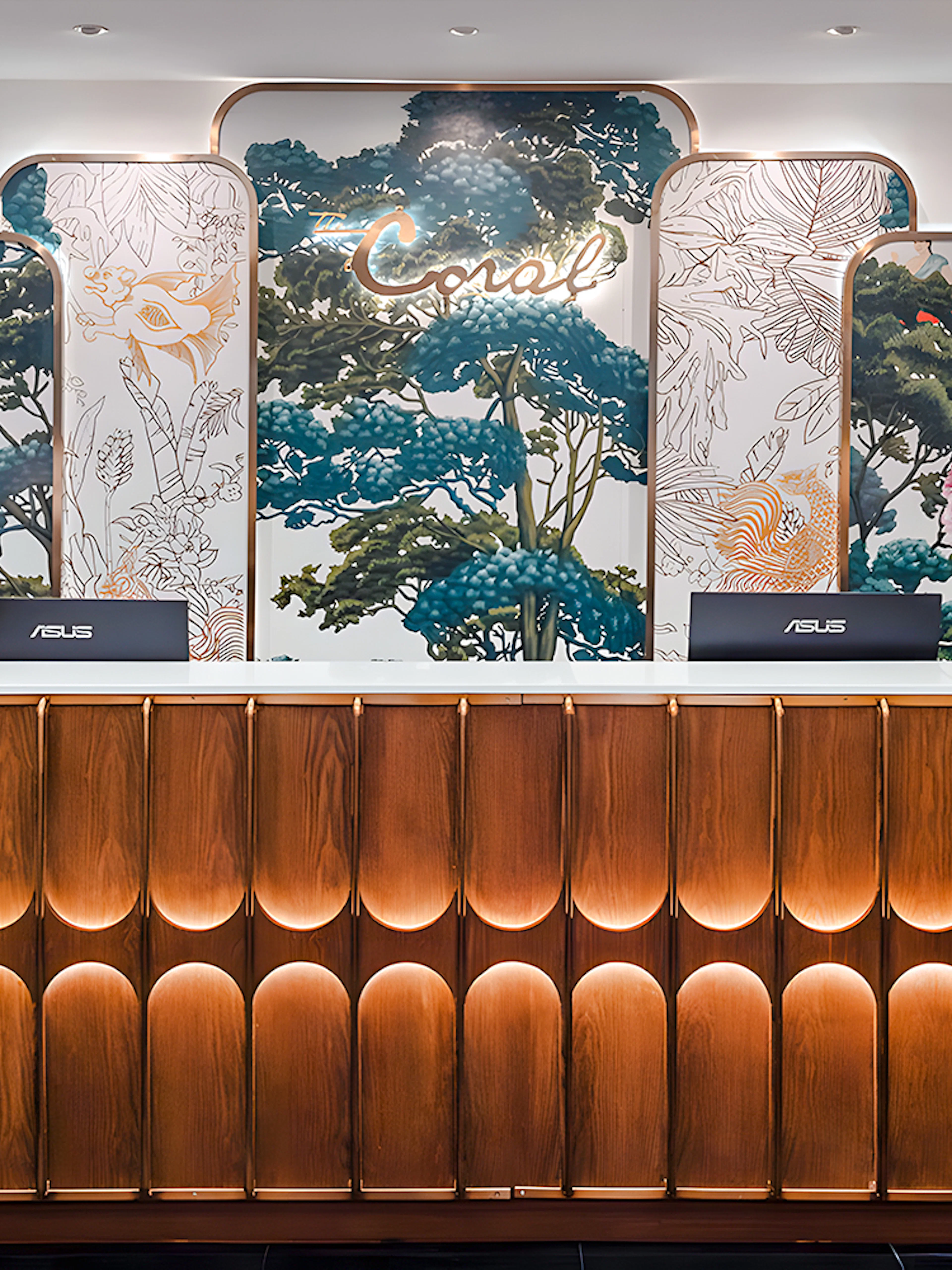 Reception desk at The Coral First Class Lounge, Bangkok airport, featuring floral decor and elegant lighting.