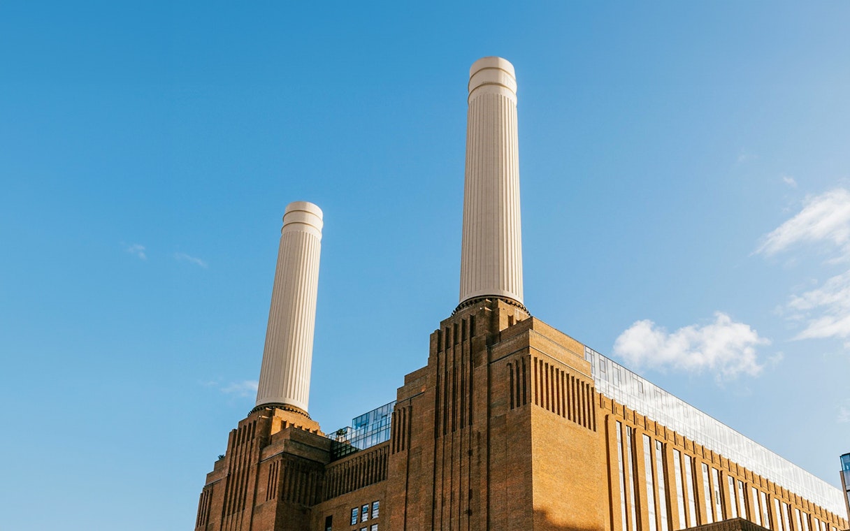 Battersea Power Station chimneys against a clear blue sky in London.