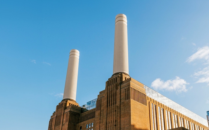 Battersea Power Station chimneys against a clear blue sky in London.