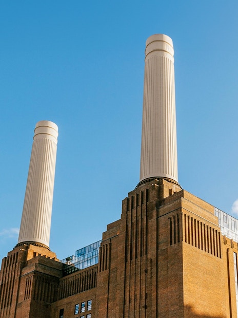 Battersea Power Station chimneys against a clear blue sky in London.