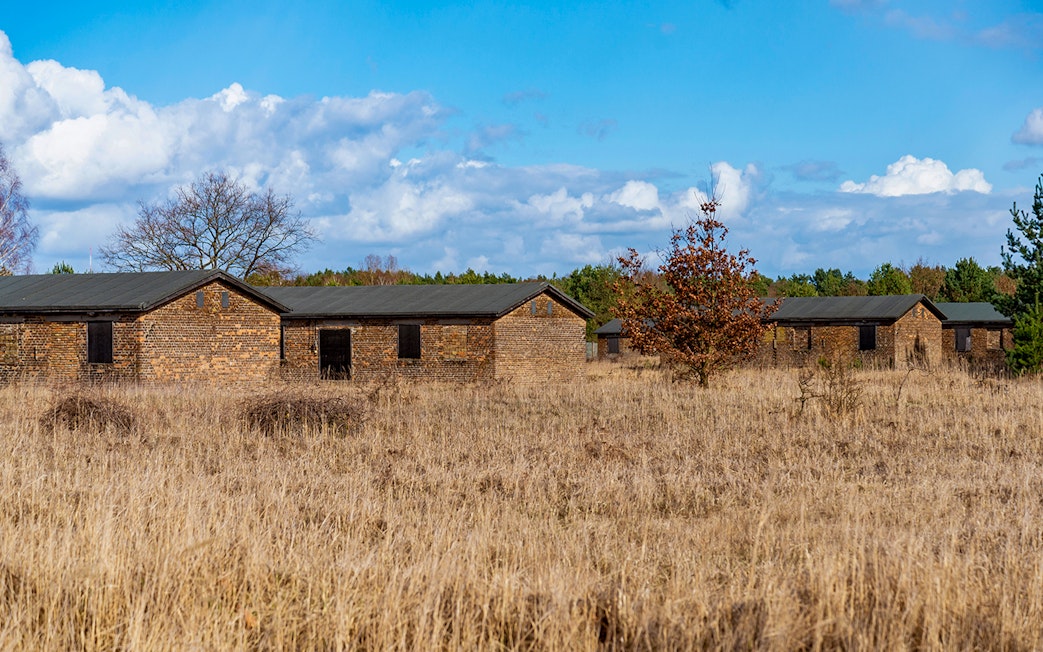 Soviet Camp No. 7 buildings in Sachsenhausen, surrounded by grass and trees under a blue sky.